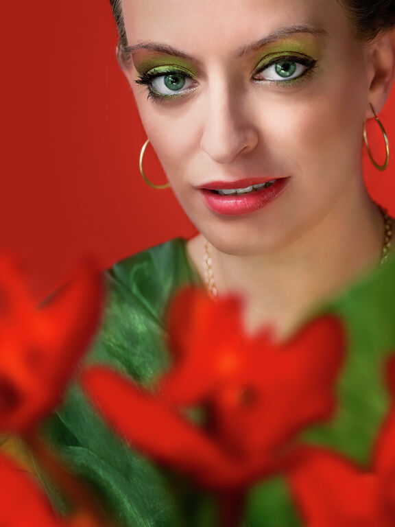 Rote Blüten vor grünem Schal. Portrait-Komposition in grü-rot-